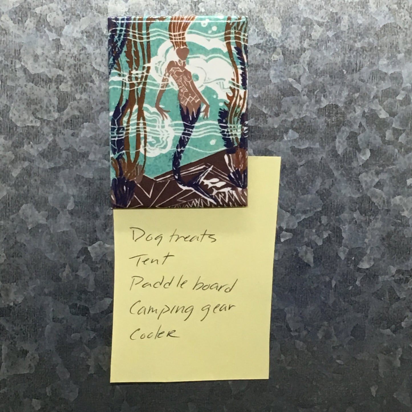 Mermaid magnet holding a list on metal surface.