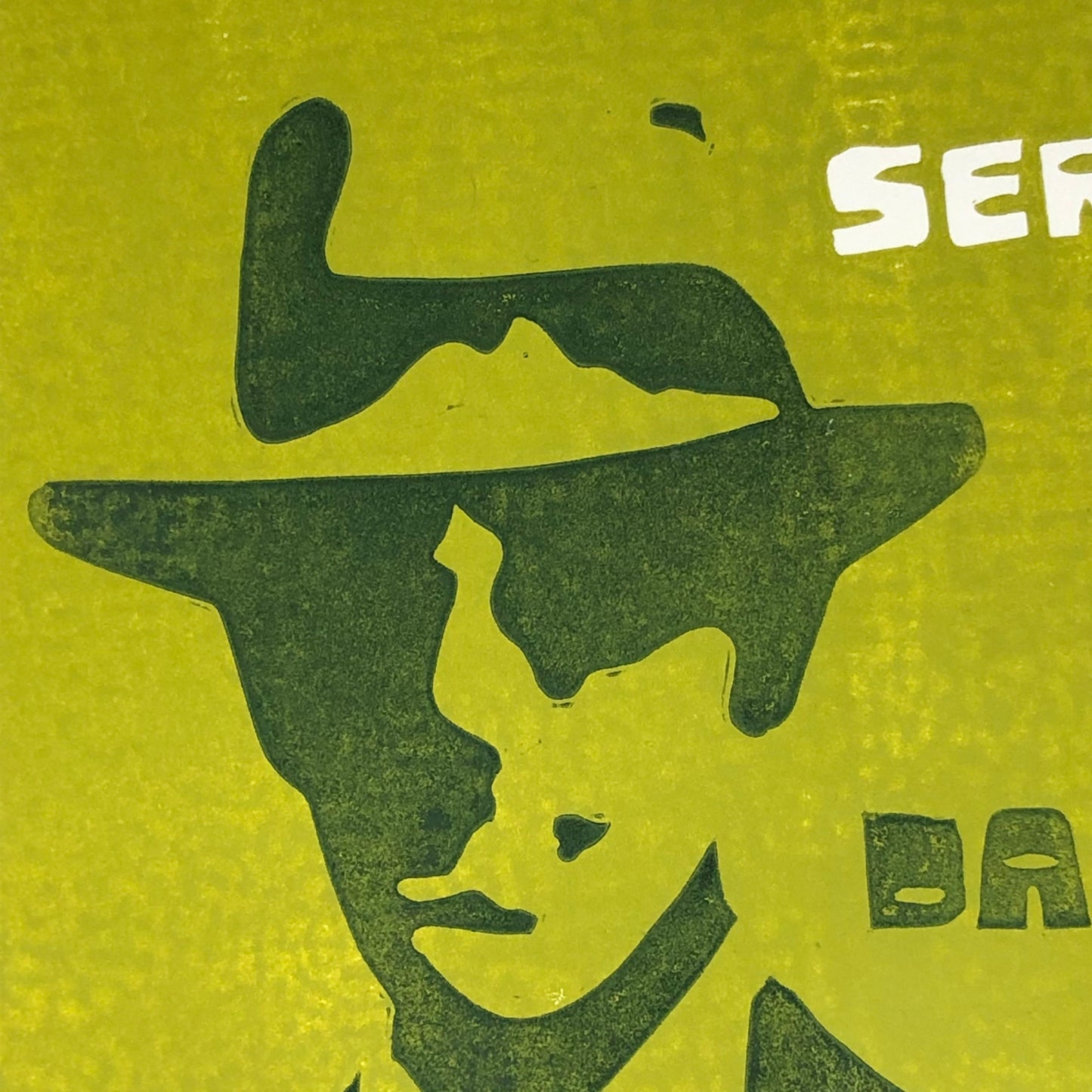 Close up of forest green silhouetted mod man with fedora hat on olive green background.